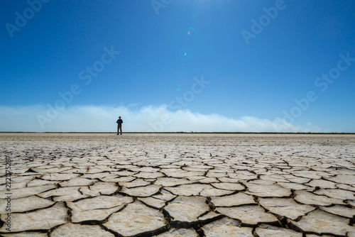 Tourist out on dry cracked mudflats at Derby