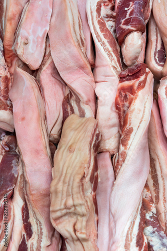 Fresh raw pork belly slices with layers of fatty meat, uncooked bacon and pork cuts strips prepared as a food ingredient, top view for unhealthy cholesterol background in super market or store mall