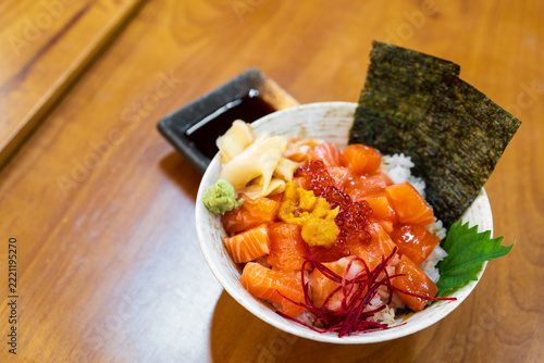 Rice bowl with raw salmon and caviar shrimp roe with seaweed sheets pickled ginger and wasabi on wooden table for healthy and fresh fish to sashimi by Japanese food in seafood restaurant with space