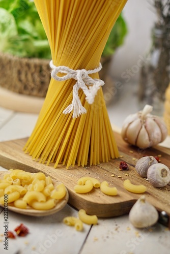 Raw Spaghetti Pasta Tied with White String and Macaroni on Wooden Board