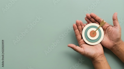 Business target symbol held in hands with an arrow hitting bullseye representing strategy and marketing success