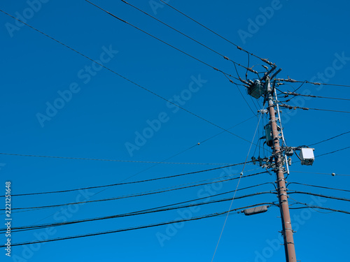 青空を背景に伸びる電柱と電線　電力供給と社会インフラ