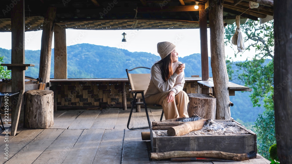 Fototapeta premium A woman sitting on wooden terrace and looking at nature views