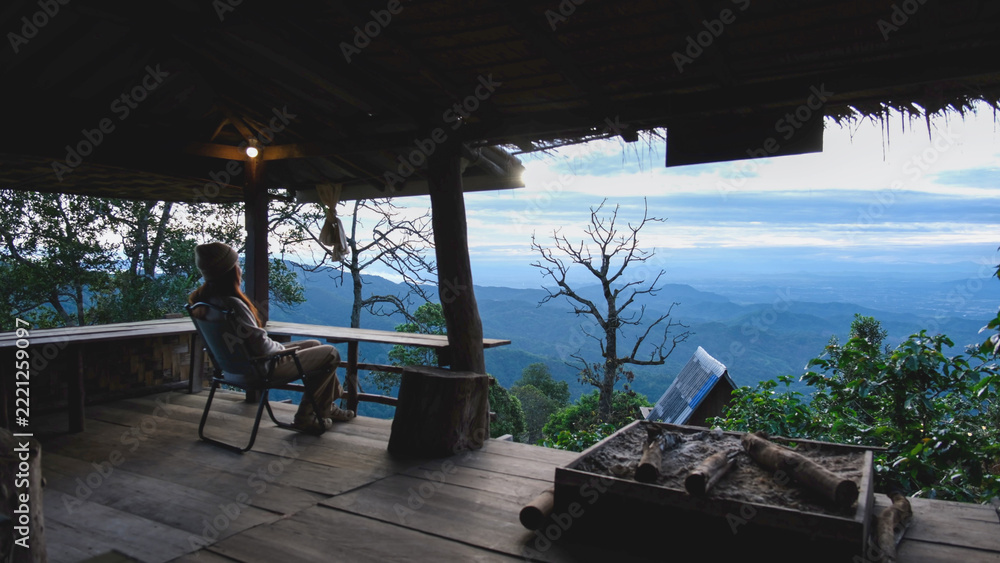 Fototapeta premium A woman sitting on wooden terrace and looking at nature views
