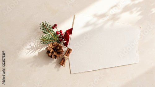 Premium Christmas Flat Lay with Large Blank Cream Greeting Card, Natural Pine Cone, Green Spruce Needles, Red Berries and Dramatic Golden Hour Window Shadows