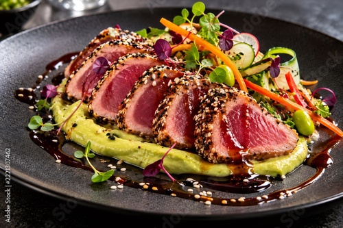 Seared tuna slices with sesame seeds on avocado puree