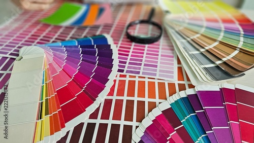 Color swatches and palettes arranged on a table with a magnifying glass for selecting colors concept