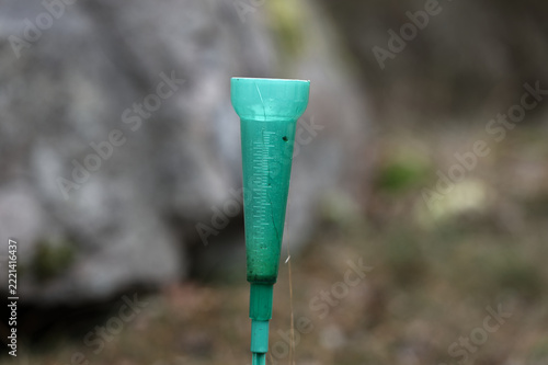 Green Plastic Rain Gauge in a Natural Outdoor Setting