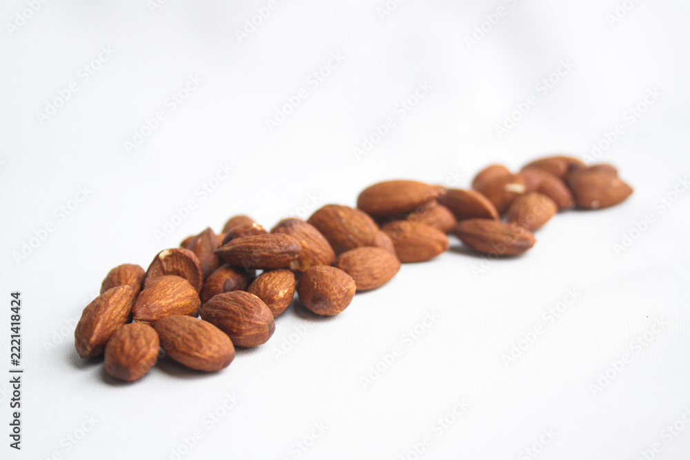 Fototapeta premium Row of roasted almond nuts arranged on a white background
