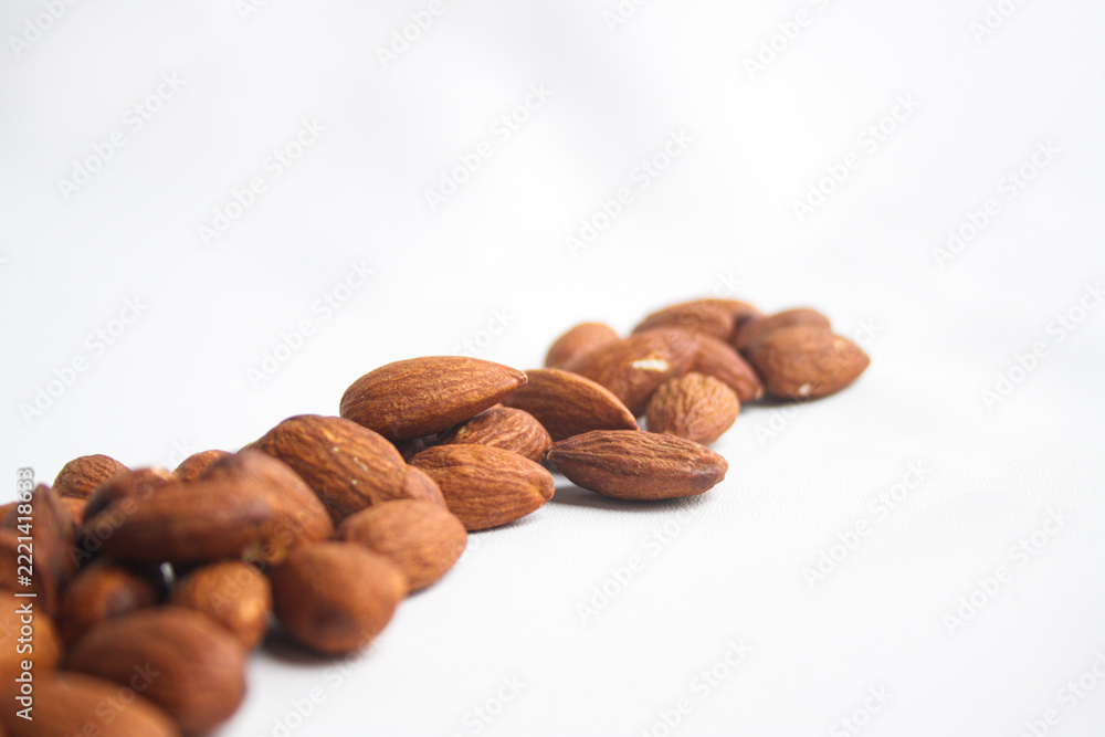 Fototapeta premium Row of roasted almond nuts arranged on a white background