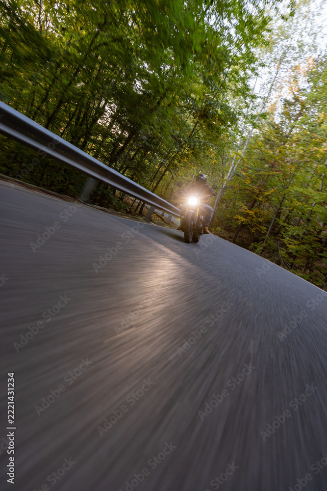 Fototapeta premium Motorcyclist Riding a Forest Road at Dusk