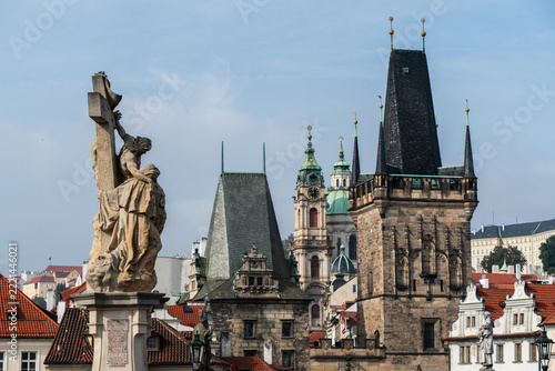 Historic stone statues and medieval towers overlooking the red rooftops of old town Prague city