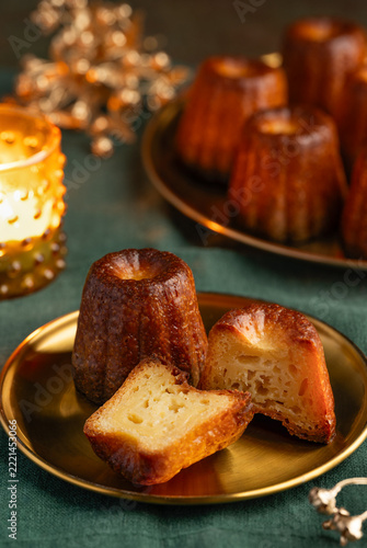Two canelés on a gold plate. A traditional French dessert with rum and vanilla and a caramelized  crispy crust. Selective focus.