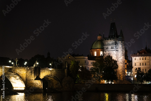 Illuminated Charles Bridge and historic architecture in Prague at night under dark sky