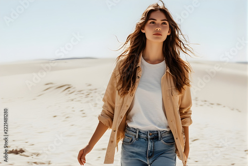Beautiful young woman walking in the desert with long hair blowing in the wind wearing casual clothes.
