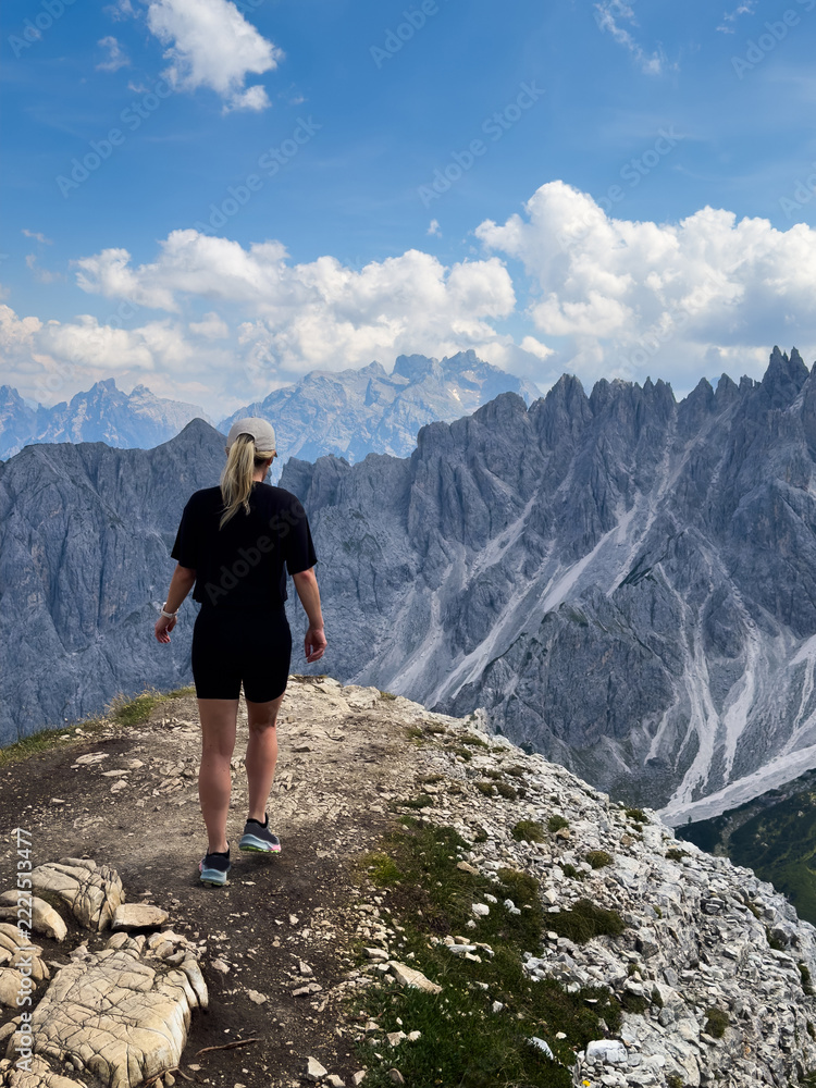 Fototapeta premium Young woman exploring hiking trail in Dolomites near Tre Cime Dolomites Italy