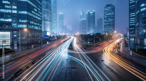 Aerial view of busy highway intersection in modern city at night with light trails from moving vehicles under towering skyscrapers in foggy atmosphere with cinematic lighting effects