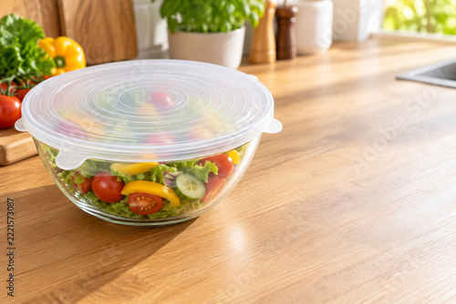 Reusable Silicone Stretch Lid Covering Fresh Vegetable Salad in Glass Bowl on Kitchen Counter