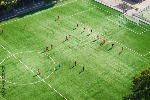 Aerial drone view of a football match on a green field. Players competing during a sports game on a stadium pitch.