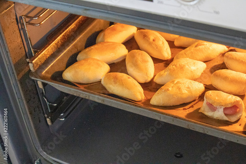 The concept of cooking homemade food, freshly baked hot pies with filling on a baking sheet in the oven
