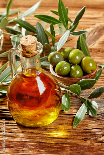 Olive oil bottle and fresh green olives with leaves