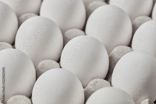 Fresh white eggs arranged in carton on gray background