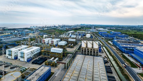 High angle aerial view of a large petrochemical refinery plant with complex processing pipes, storage tanks, and factories under a daylight sky.