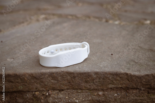 White Silicone Identification RFID Wristband Lying on an Outdoor Stone Pavement Surface