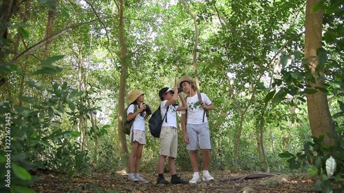 Children with binoculars holds hands and looks into distance and something joyfully screams they are wearing save world t-shirt with forest nature summer travel holiday concept.