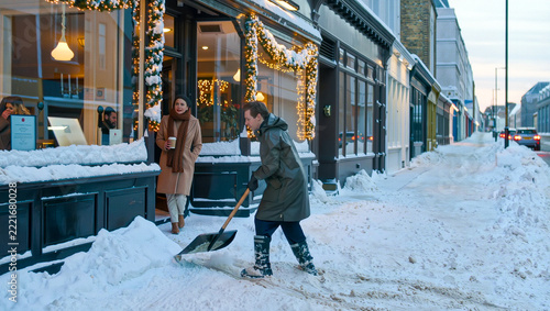 A worker shovels deep snow from a sidewalk