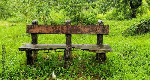 Old weathered concrete bench standing on vibrant green grass field in outdoor garden park