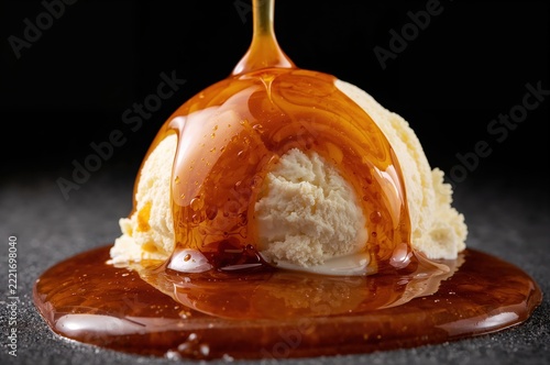Caramel sauce pouring over creamy vanilla ice cream scoop macro dessert closeup