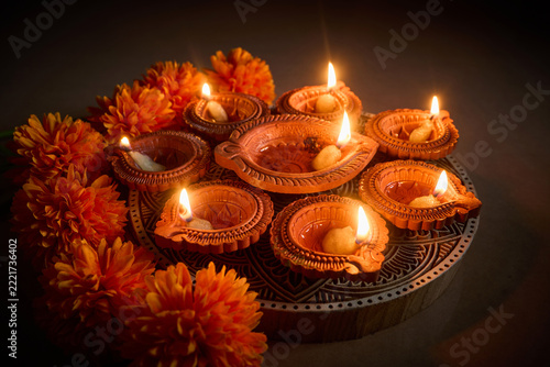 Diwali clay oil lamps with glowing flames and marigold flowers