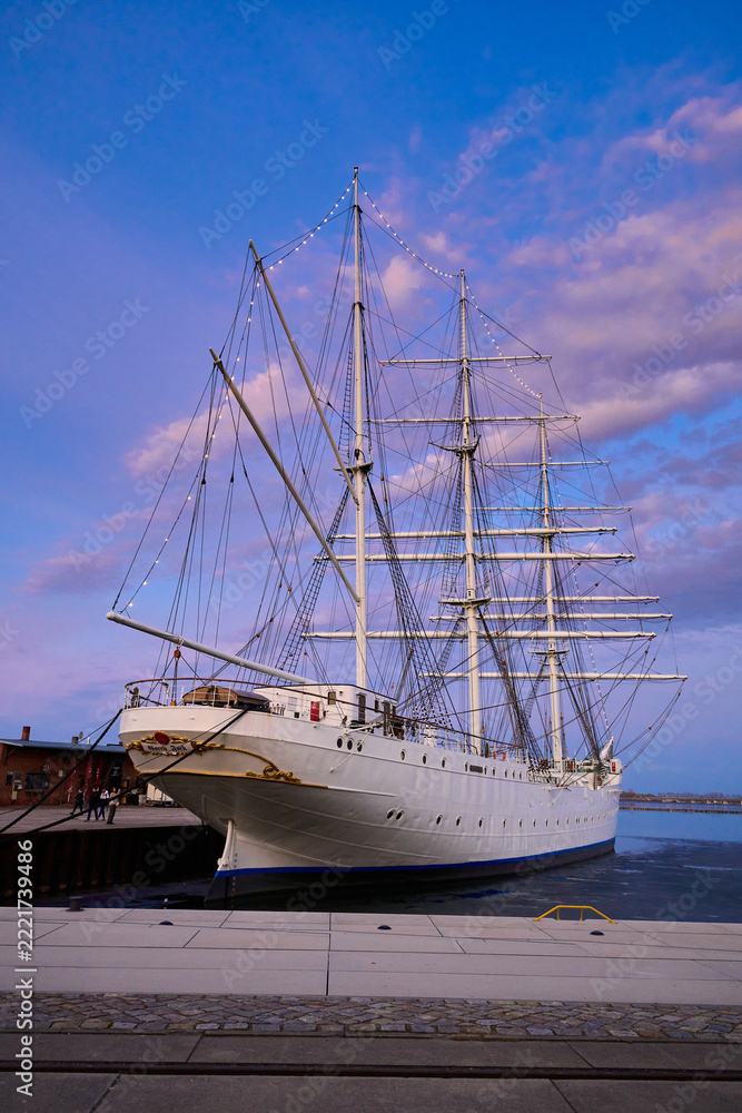 Fototapeta premium Historic Sailing Ship Docked at Sunset in a European Harbor