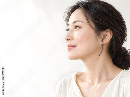 柔らかな自然光に照らされた艶やかな頬と上品な横顔の女性 白い背景に映える透明感のある美肌とスキンケア美容向けの広いコピースペース