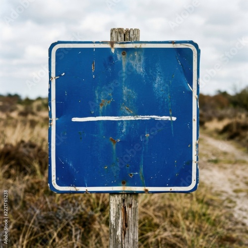 Weathered blue road sign with horizontal white line on rustic wooden post in dry grassy landscape overcast sky