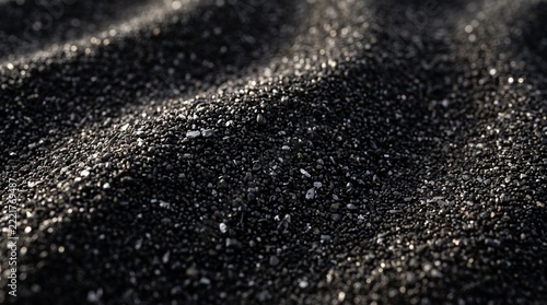 Close up of black volcanic sand ripples on beach with sunlight