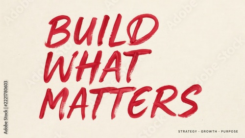 Red handwritten text Build What Matters on off-white paper texture. This motivational quote represents business strategy and corporate purpose concepts for professional branding.