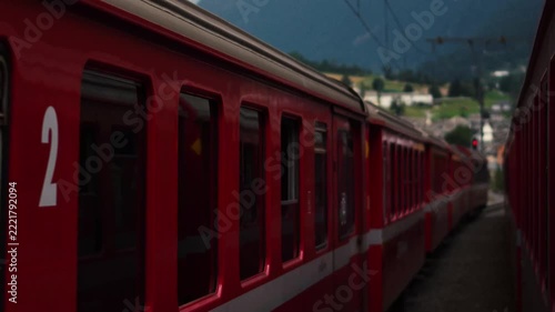 Red passenger train passing by on railway track in scenic mountains