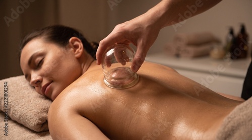 Woman receiving glass cupping therapy on back in spa setting with copy space