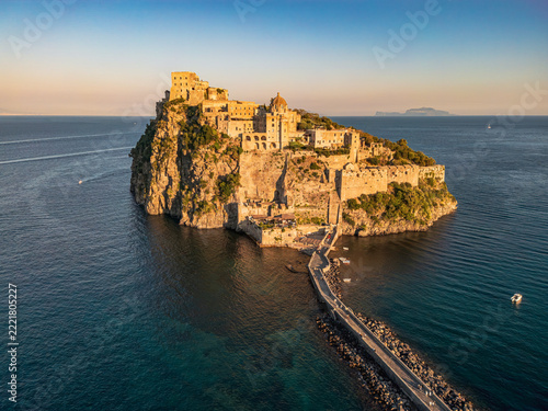 Golden hour over the Aragonese Castle, Ischia.
ISCHIA, ITALY - OCTOBER 4, 2026: Aerial view of the historic Aragonese Castle perched on a rocky islet connected by a stone bridge during golden hour.