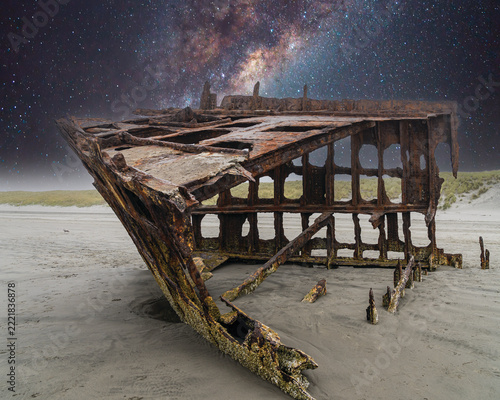 The Peter Iredale, a four masted steel hulled transport ship, built in England, round aground in 1906 and remains on the shore of the Oregon Coast in the Pacific Ocean in a star filled night sky