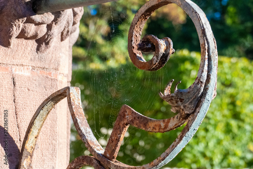 Spinnennetz an einem alten, verosteten Ornament am Geländer