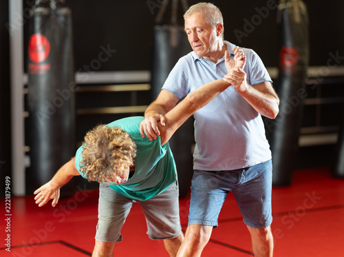 Fotografie Determined elderly man working on defensive grips and escape technique with part