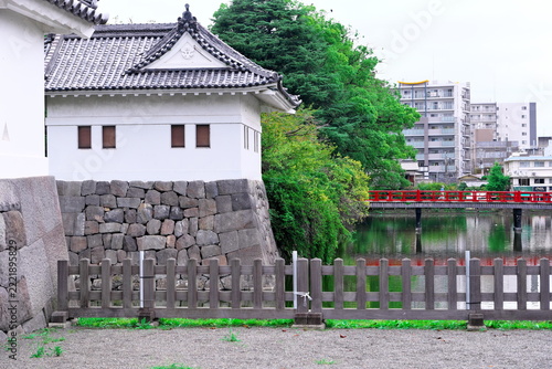 Japanese castle turret standing by moat with red bridge
