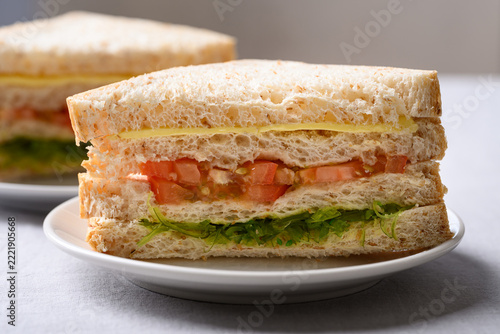 Whole wheat bread sandwich with cheese, tomato and wakame seaweed on white plate