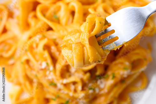 Eating butternut squash pasta topped with grated parmesan cheese and fresh herbs, Autumn seasonal food, Top view