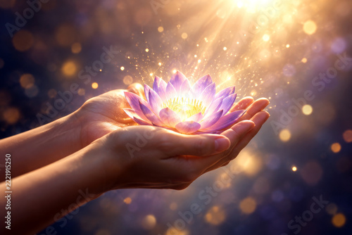 Hands holding glowing lotus flower with divine light rays and sparkles in meditation concept