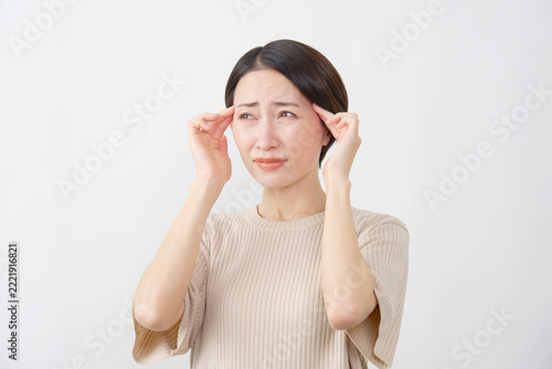 Fotografie 白背景で両こめかみを押さえる40代女性