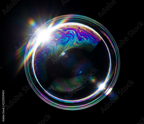 macro iridescent soap bubble with rainbow light reflection on black background